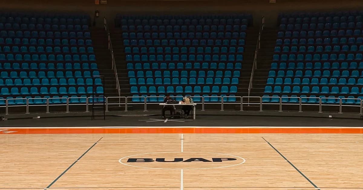 Empty indoor basketball court with blue arena seating